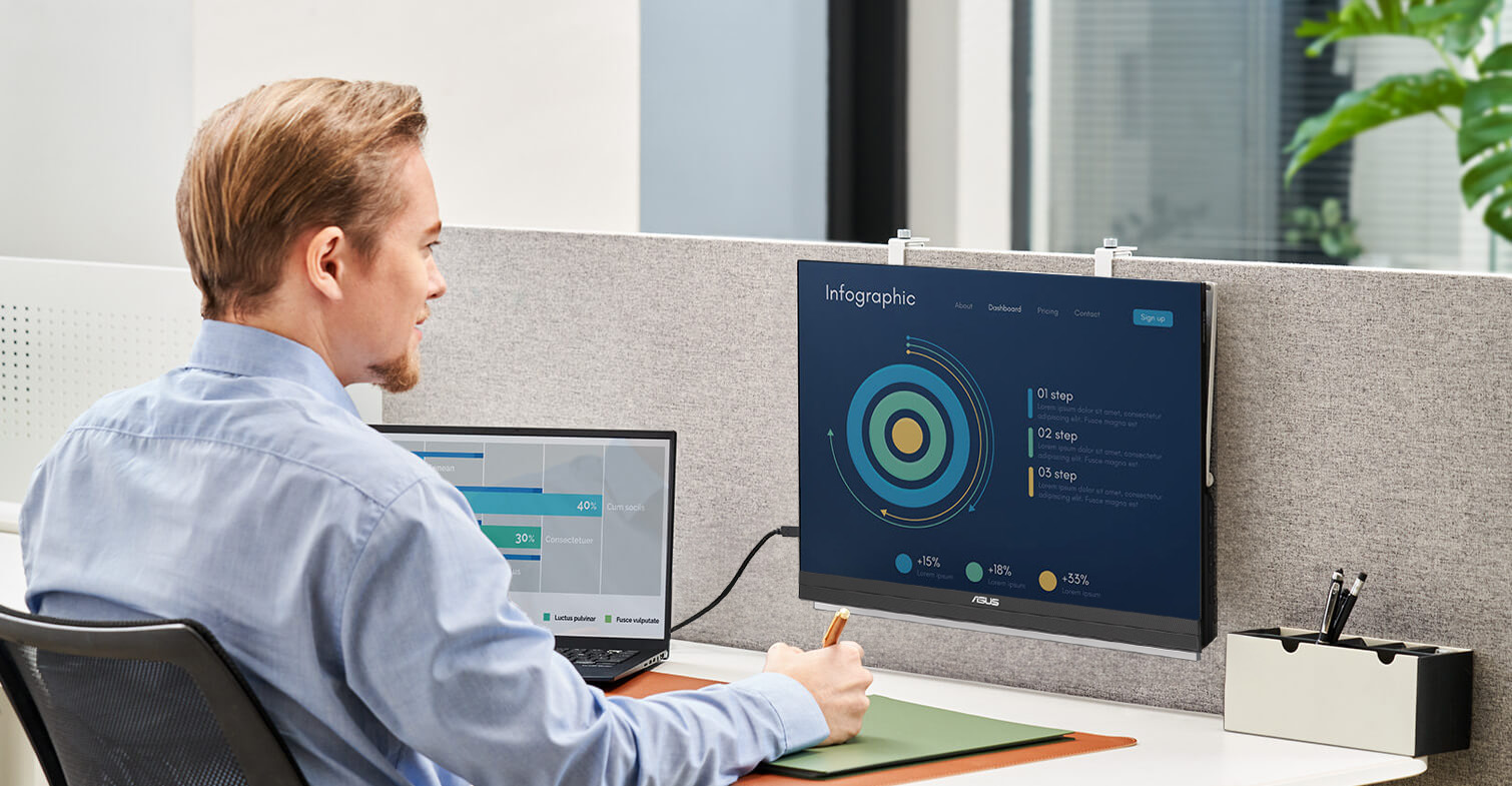 Ein Mann arbeitet im Büro mit einem Laptop und einem ZenScreen MB229CF auf einem Partitionshalter