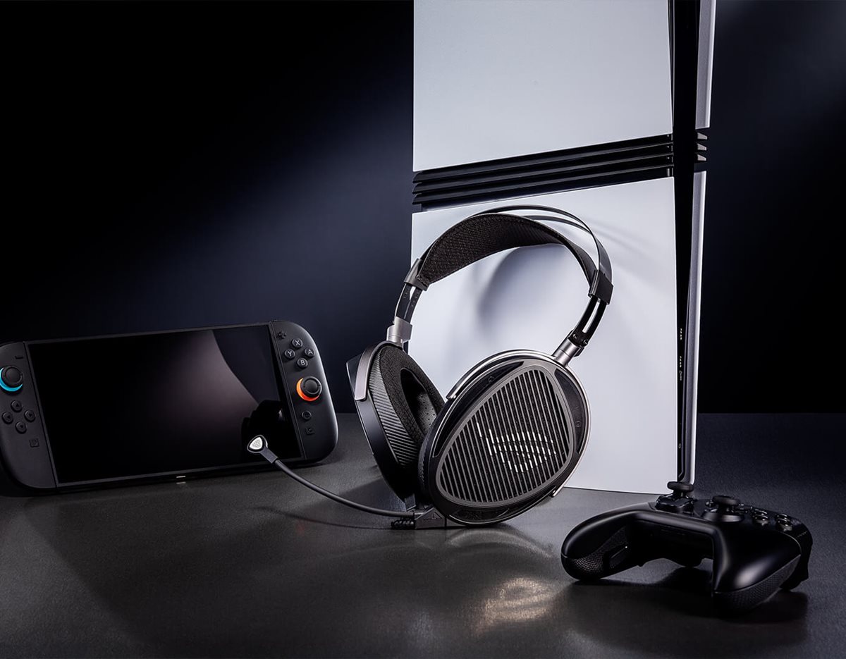 ROG Kithara-Headset neben einer Spielkonsole, einem kabellosen Gamecontroller und einem Handheld-Gaming-Gerät auf einer dunklen Fläche.